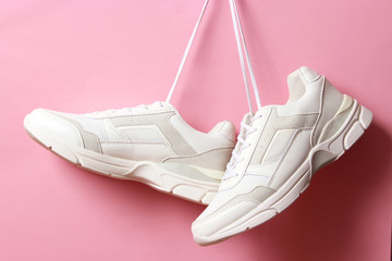  Modern trendy sneakers hang on laces on a colored background. Casual shoes, sports shoes. Place to...