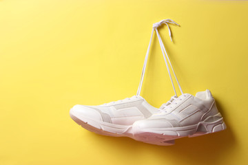  Modern trendy sneakers hang on laces on a colored background. Casual shoes, sports shoes. Place to...