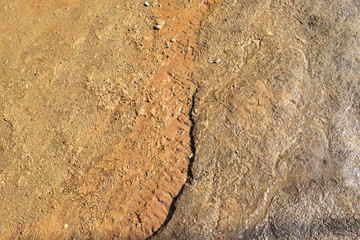 Earth textured surface background. Water flows on the ground. Little creek.