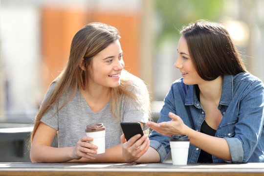 Friends Talking About Phone Content In A Park