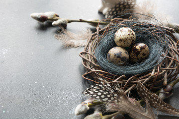 Quail easter eggs in nest and spring willow on vintage table.