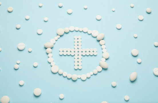 Cross of white pills on blue background. Medical care, ambulance.