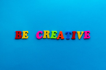 text be creative from plastic colored letters on blue paper background