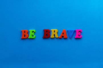 text be brave from plastic colored letters on blue paper background
