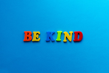 text be kind from plastic colored letters on blue paper background