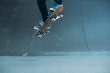 Skateboarder in action. Extreme sports lifestyle. Hipster feet performing ramp trick. Cropped shot. Copy space.
