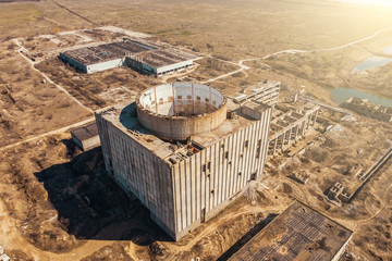 Aerial view of abandoned and ruined Nuclear Power Plant. Huge building with round whole for reactor in roof without celling
