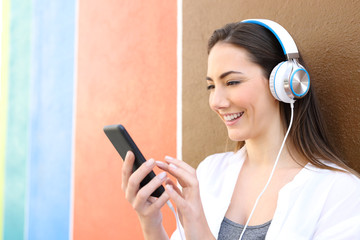 Happy woman listening to music using phone outdoors