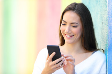Fototapeta na wymiar Happy woman using smart phone in a colorful wall