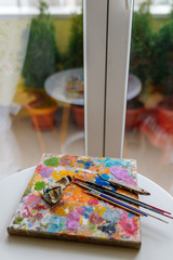 Naklejka na ściany i meble Artistic paint brushes and palette in the studio 
