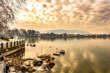 Scenery of Ioannina city lit up by red,orange colors sunlight  and glowing sky with reflections on...