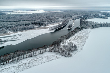 Winter landscape with a river flowing through the winter forest.