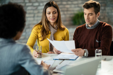 Mid adult couple analyzing documents while being on a meeting with a lawyer.