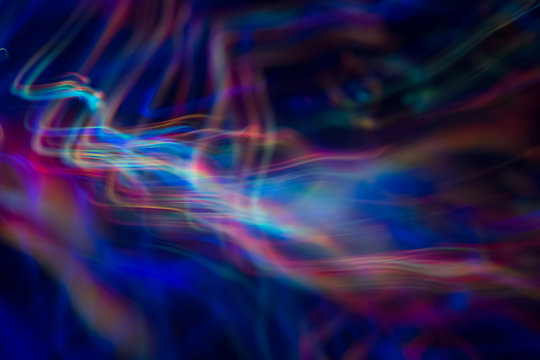 Blurry abstract background with wavy multicolor lines. Neon lights in motion. Defocused lens flare glow.