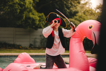 Kid playing pirate on inflatable mattress in pool
