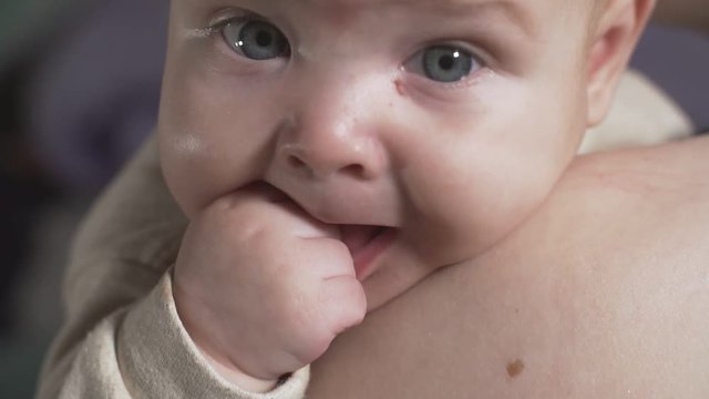 Cute little baby looking at camera in mother's hands. Concept of caring for children and parental love
