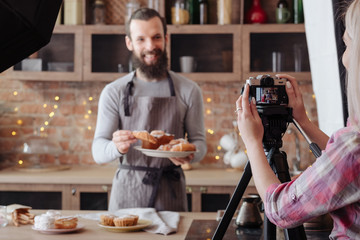 Cooking man. Baking. Excited chef in apron with plate of fresh cakes and pastries. Backstage photography.