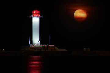 Vorontsov Lighthouse night against the rising of the big red moon. Old white beacon lantern...