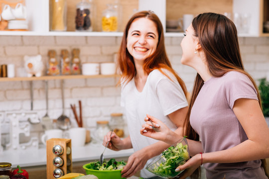 Dieting Together. Female Cooking Fun. Two Young Women With Salad Bowls Laughing Loud.