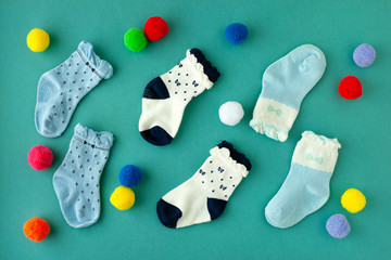 Socks for children on a colored background. View from above. Children's multi-colored socks scattered on a turquoise background. Clothing for children in the form of socks.
