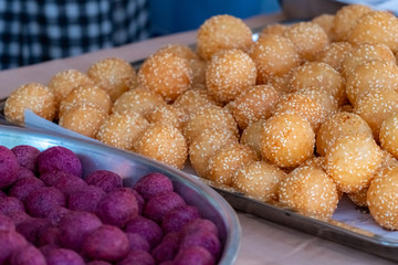 Thai traditional dessert. Deep fried sesame balls and deep fried sweet potato balls on stainless steel tray of seller. Purple and brown sweets balls.