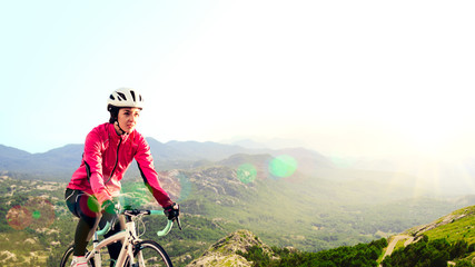 Young Woman in Bright Pink Jacket Riding Road Bicycle on Mountain Alpine Road. Healthy Lifestyle and Adventure Concept.