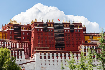 Close up of main part of Potala Palace with mighty white cloud in the background. The national flag...