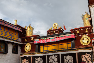 LHASA, TIBET / CHINA - July 31, 2017: Side view on roof of Jokhang Temple with golden prayer wheel,...