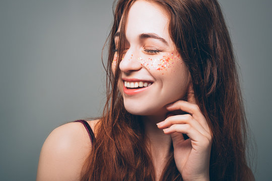Young woman beauty. Freedom and happiness. Smiling redhead female. Eyes closed. Sparkles on cheeks.