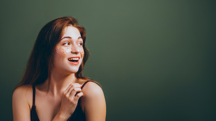 Wow girl. Happy facial expression. Smiling young woman looking sideways. Copy space on green background.
