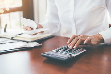 Woman with bills and calculator. Woman using calculator to calculate bills at the table in office. Calculation of costs.