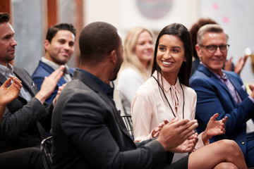 Group Of Businessmen And Businesswomen Applauding Presentation At Conference