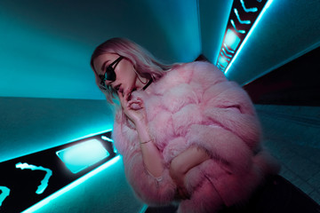 Teen hipster girl standing in neon lights on street, portrait