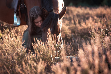 Pferd und Reiterin kuscheln in der Heide