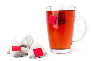 Red tea glass cup with tea bags isolated on white background. Fruit tea with triangle tea bags in cup. 