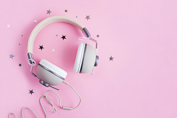 Retro headphones and stars glitter confetti on pink background.