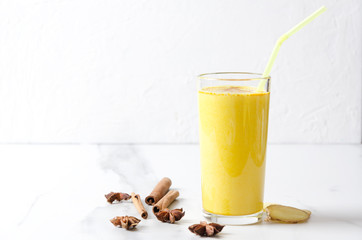 Delicious golden milk with different spieces on marble table against white wall. Empty space for your design