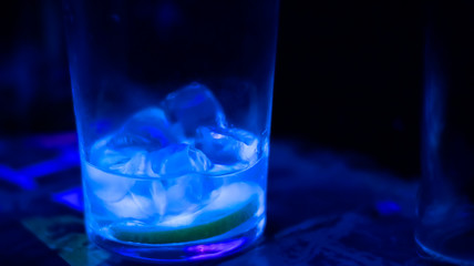 almost finished cocktail - Bright glass and ice cubes - Dark background
