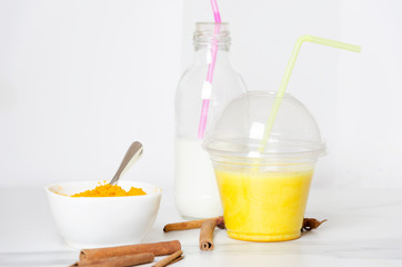 Cup of golden milk,bottle of milk, turmeric, cinnamon. Ingredients fortasty turmeric latte