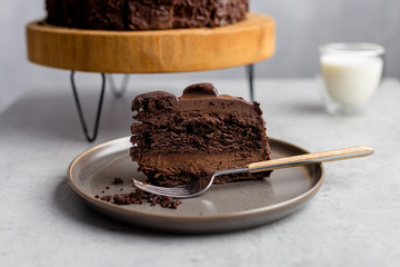 Piece of chocolate cake on plate with fork on gray background