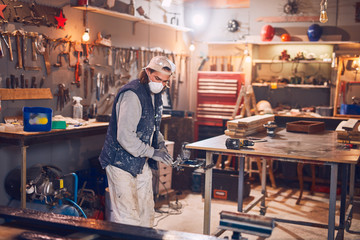 Male carpenter working on old wood in a retro vintage workshop.