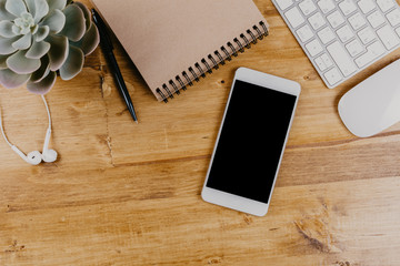 Top View of trendy wooden Office Desk with keyboard, white earphones and office supplies.