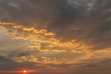 Dramatic sunset sky with orange colored clouds and last rays of the sun, colorful evening background