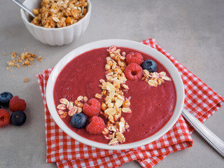 Smoothiebowl mit roten Früchten in einer weißen Schüssel, rustikaler Stil