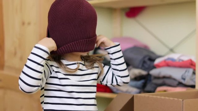 Funny baby girl is putting on hat at home