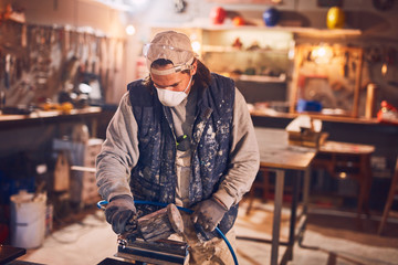 Male carpenter working on old wood in a retro vintage workshop.