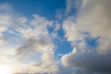 Naklejka na ściany i meble Clouds in a blue sky in sunlight at sunrise in spring