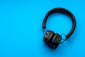 Black stylish headphones on blue background.
