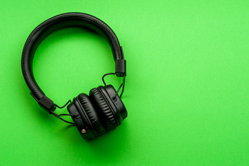 Black stylish headphones on green background.