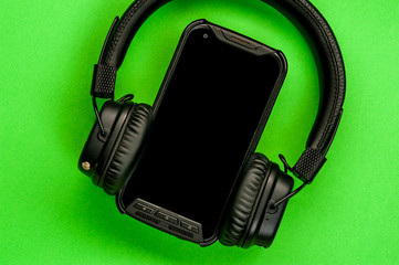 Black stylish headphones on green background.